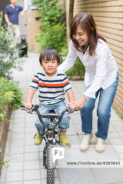 Mutter hilft dem Sohn beim Radfahren
