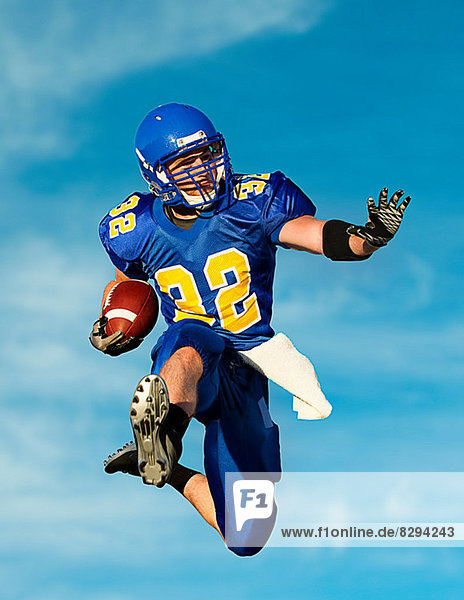 American Footballer mit Ball gegen blauen Himmel