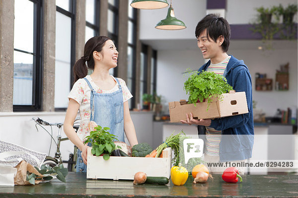 Portrait of young couple in kitchen with herbs and vegetables