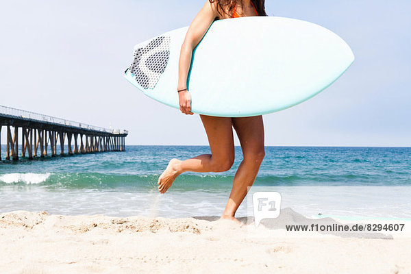 Woman running with surfboard  Hermosa Beach  California  USA