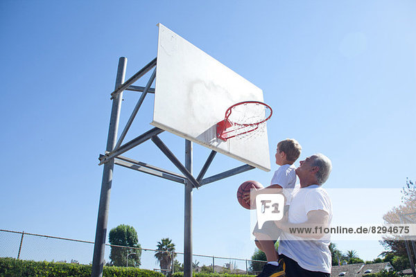 Mann hebt Enkel auf Basketballkorb