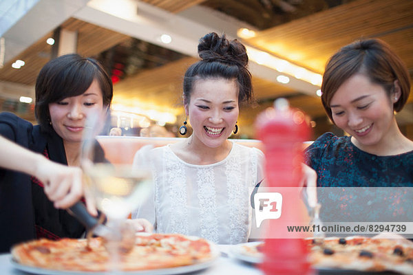 Young women eating pizza in restaurant