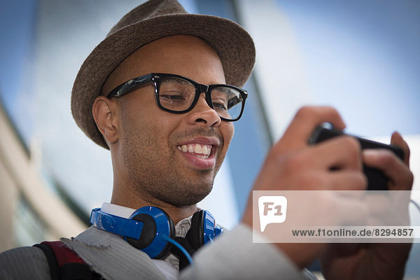 Junger Mann mit Hut und Brille mit mp3-Player