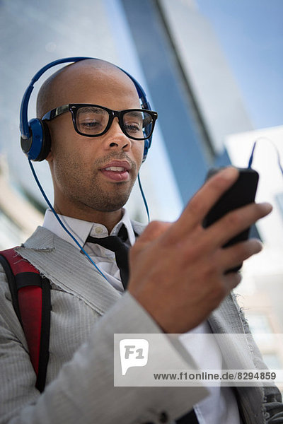 Young man wearing headphones and glasses using mp3 player