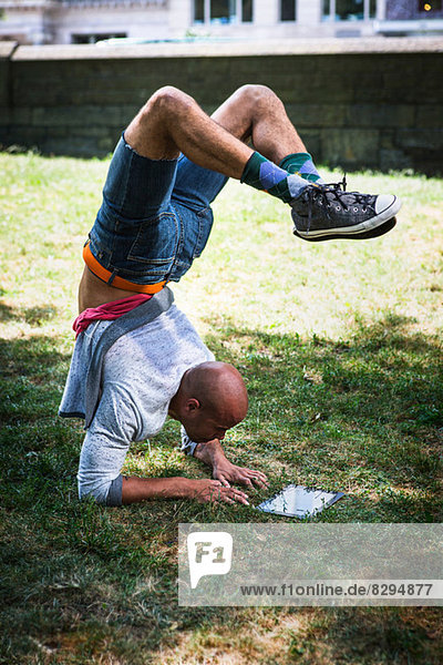 Young man doing handstand using tablet