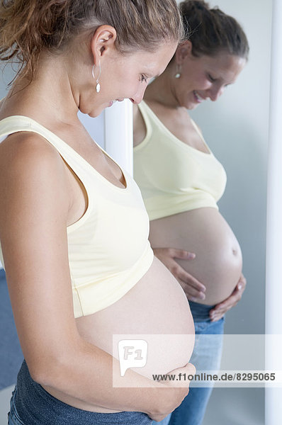 junge schwangere Frau vor dem Spiegel