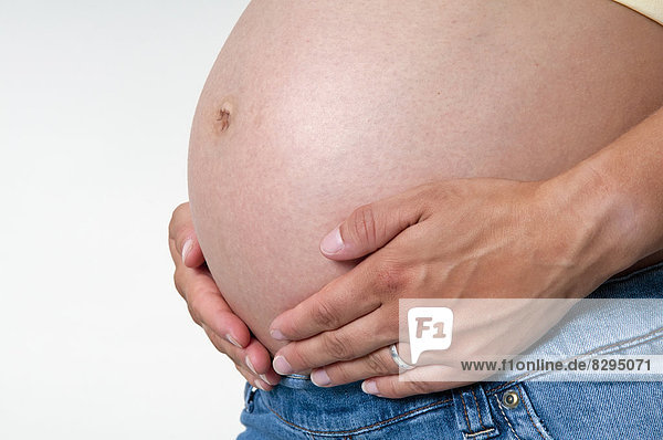 Hände auf schwangeren Bauch  Studioaufnahme