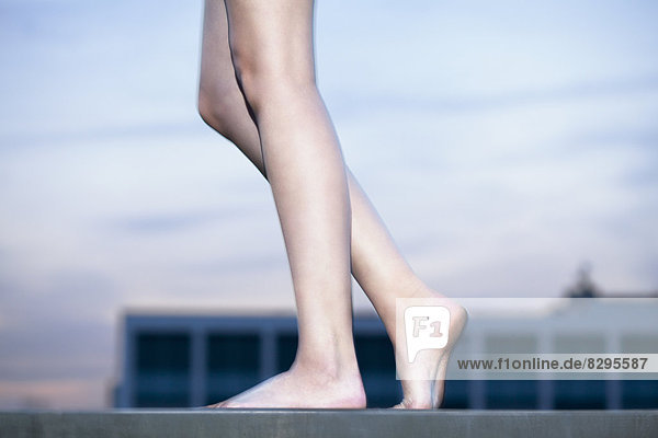 Nackte Beine einer jungen Frau mit kleinem Tatoo auf dem rechten Fuß