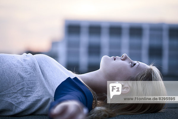 Junge Frau auf Flachdach liegend