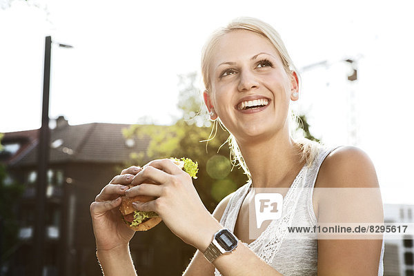 Lächelnde junge Frau mit Hamburger