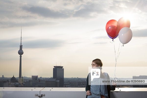 Young woman on rooftop terrace  holding balloons