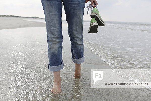 Deutschland  Niedersachsen  Ostfriesland  Langeoog  Beine einer Frau beim Strandspaziergang
