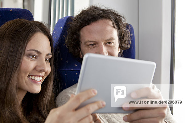 Couple using digital tablet in a train