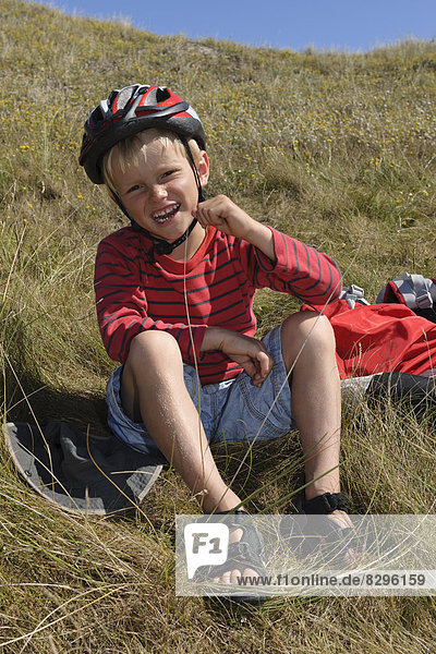 Frankreich  Bretagne  Landeda  Junge mit Helm in der Düne sitzend