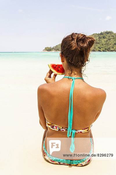 Thailand  Koh Surin island  woman eating a slice of watermelon at the white sandy beach