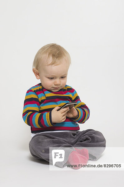Baby Junge spielt mit Smartphone  Studioaufnahme