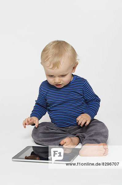 Happy baby boy playing with tablet PC,  studio shot