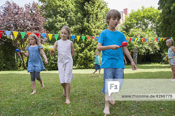 Children having a spoon and egg race in garden on a birthday party