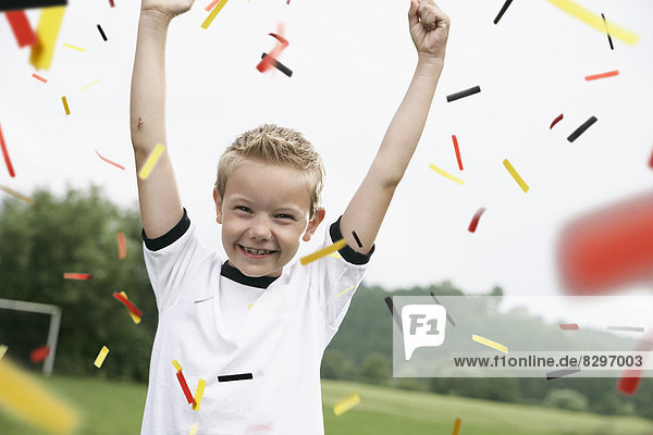 Boy in soccer jersey cheering on soccer pitch