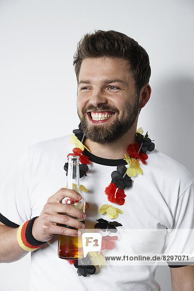 Lächelnder Mann im Fußballtrikot mit Bierflasche