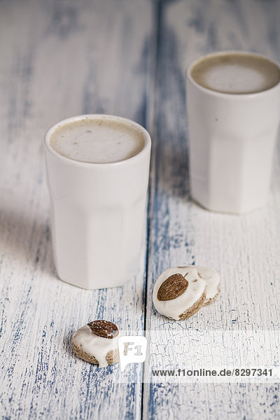 Cups of latte macchiatto with almond biscuits on wooden board