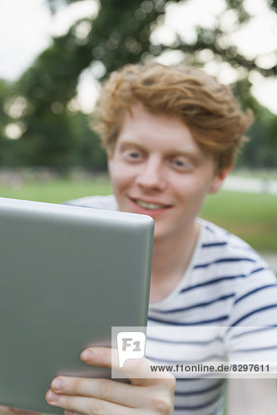Young man holding a tablet computer outdoors