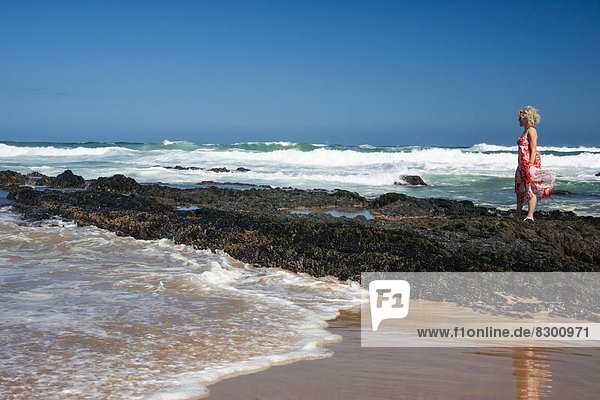 Südliches Afrika Südafrika stehend Frau Felsen Blume Ozean Indianer Wind Sonnenaufgang Afrika Kleid Garden Route