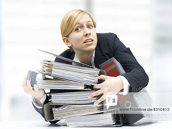 Stressed business woman holding a stack of folders