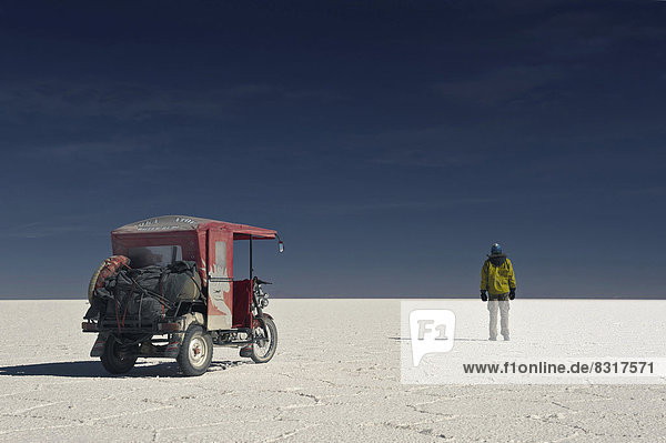 Mann und Mototaxi auf trockenem Salzsee Salar de Uyuni