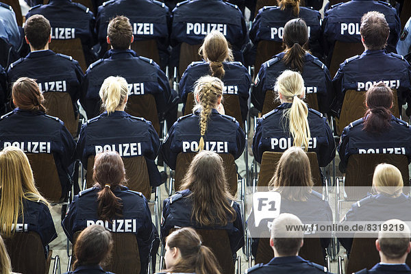 Police commissioner candidates  trainees of the Polizei NRW or North Rhine-Westphalia Police  sitting at a meeting in an auditorium