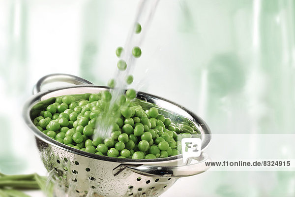 Garden peas and water splashing into a colander