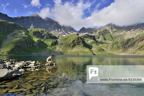 Bergsteigerin füllt Wasserflasche am Großen Schwarzsee oder Lago Nero  dahinter Schwarzwandspitze