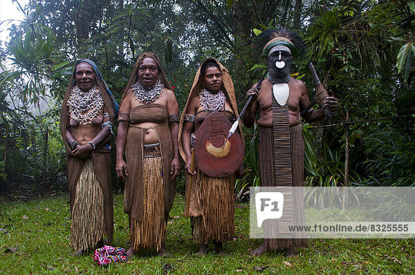Stammesoberhaupt und drei Frauen in traditioneller Kleidung