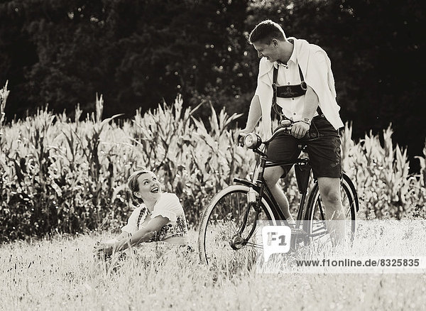 Mann und Frau in Tracht mit einem alten Fahrrad in der Natur