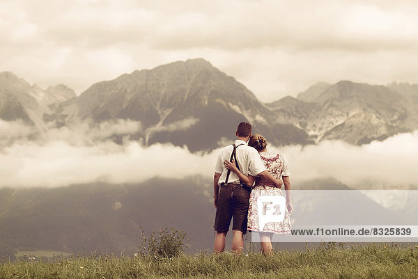 Mann und Frau in Tracht blicken auf die Berge