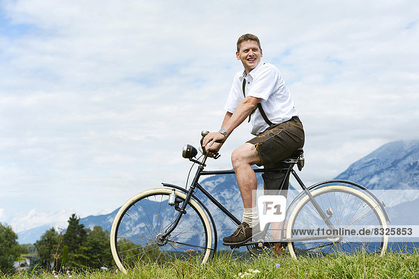 Man wearing leather pants on an old bicycle
