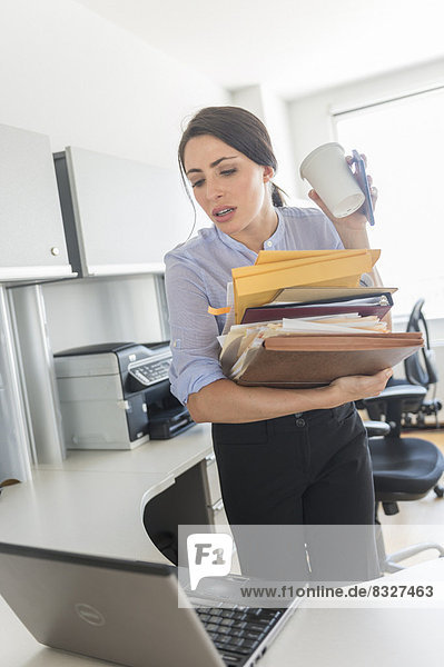 Business woman holding stack of documents and coffee cup