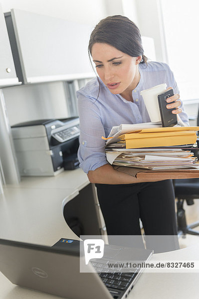 Business woman holding stack of documents and coffee cup