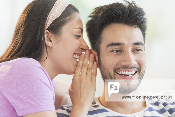 Woman whispering to man's ear