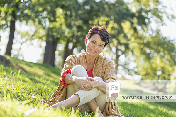 Mature woman sitting on grass in park