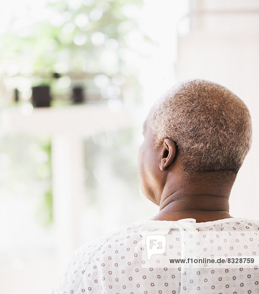 Rear view of patient wearing surgical gown and looking through window