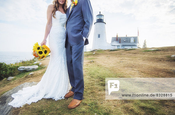 Low section of married couple  lighthouse in background