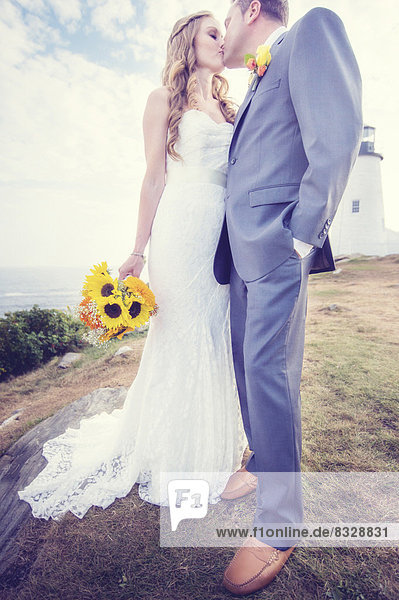 Portrait of married couple kissing  lighthouse in background