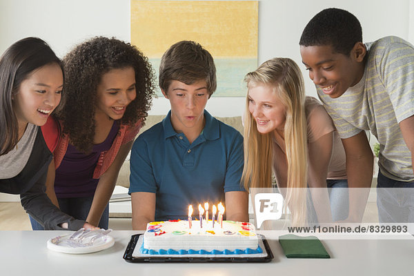 Children (12-13 14-15 16-17) blowing candles on birthday cake