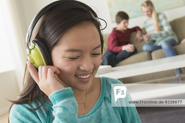 Girl (16-17) listening to music wearing headphones