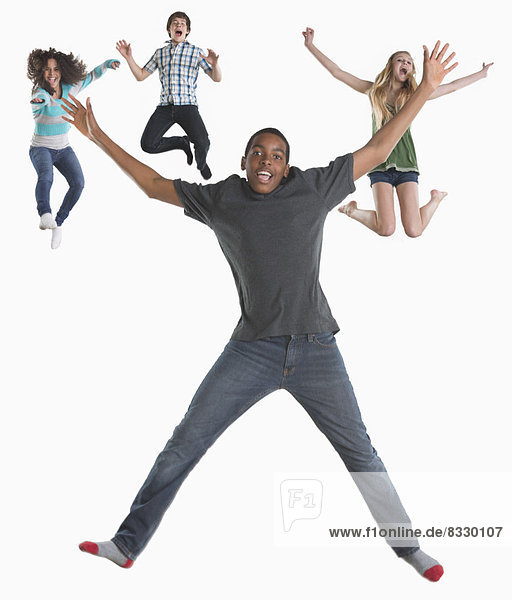 Studio shot of four friends (12-13 14-15) jumping on white background