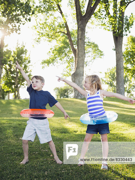 Two kids (4-5  6-7) playing with inflatable rings in park