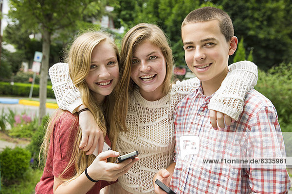 Drei junge Leute  zwei Mädchen und ein Junge  posieren und fotografieren sich selbst.