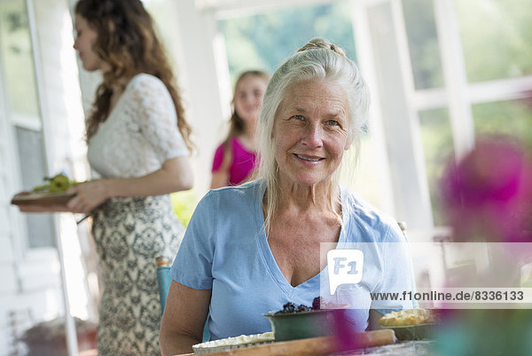 A family party in a farmhouse in the country in New York State. A mature woman holding bowl of fresh blackberries.