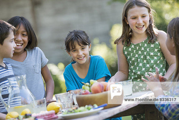 Eine Gruppe von Kindern um einen Tisch  die frisches Obst und Salate essen.